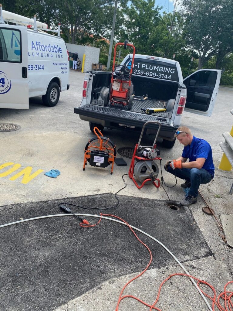 Plumber using a snake and scope camera on a sewer line for a clogged pipe at a commercial location